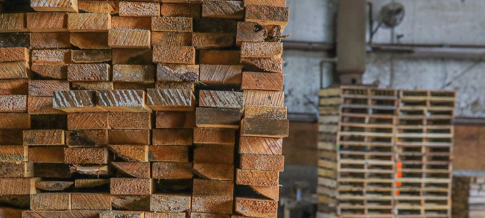 A close of new lumber with pallets in the background