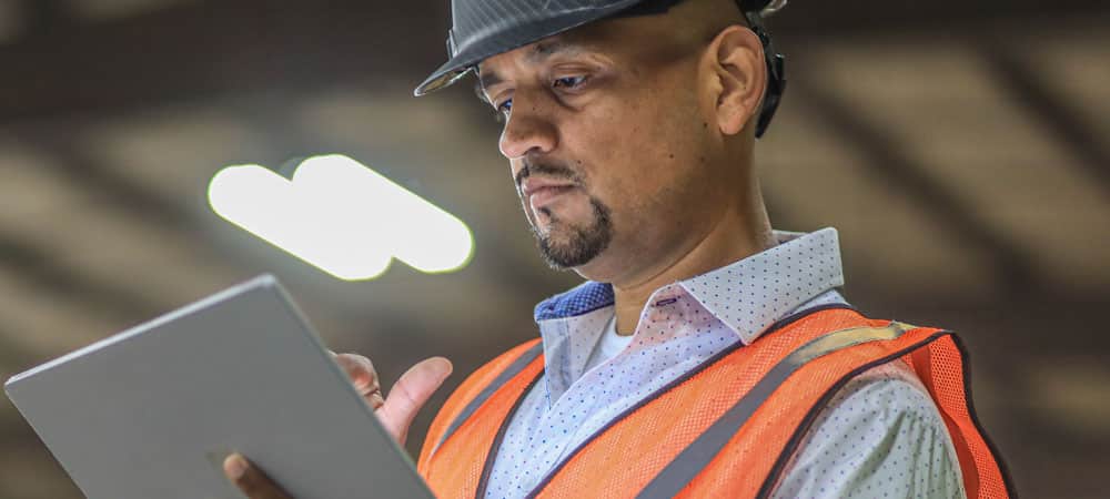 Kamps Employee looking at a tablet wearing safety vest and helmet