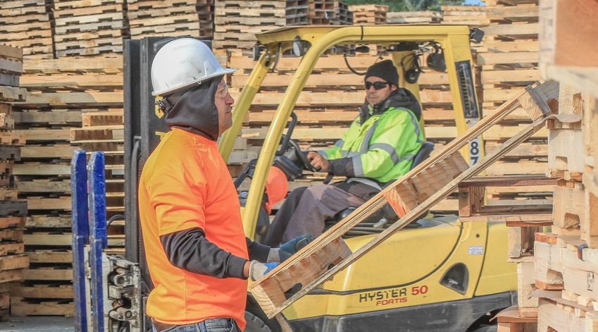 Kamps Detroit employee holding a wooden pallet