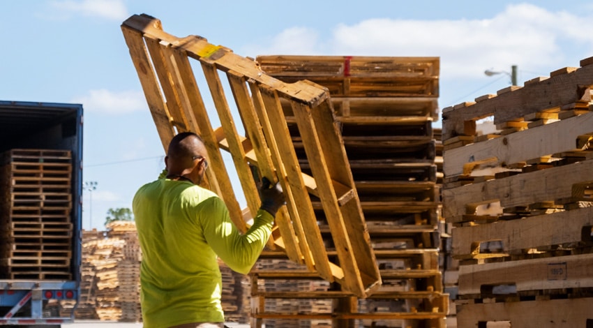 Kamps Employee Carrying a reconditioned wooden pallet