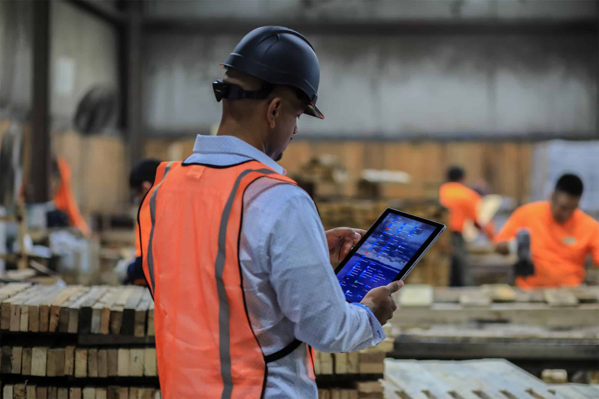 Manager of a pallet company with a hard hat and tablet inside pallet facility