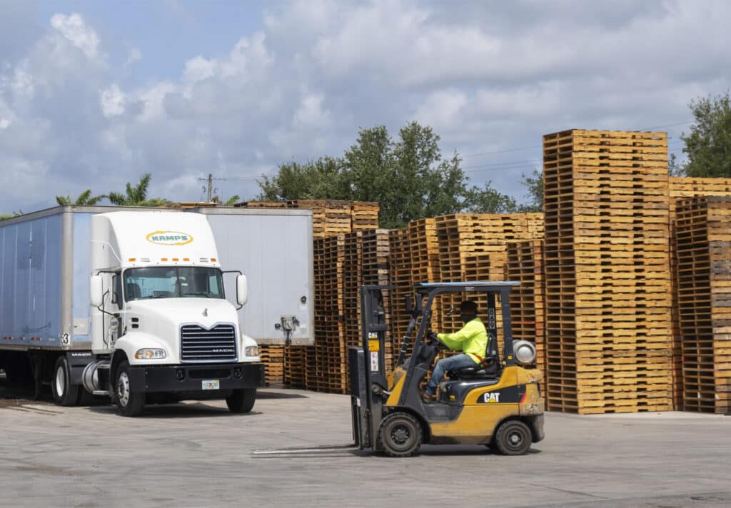 Forklift driver passing through wooden pallets yard