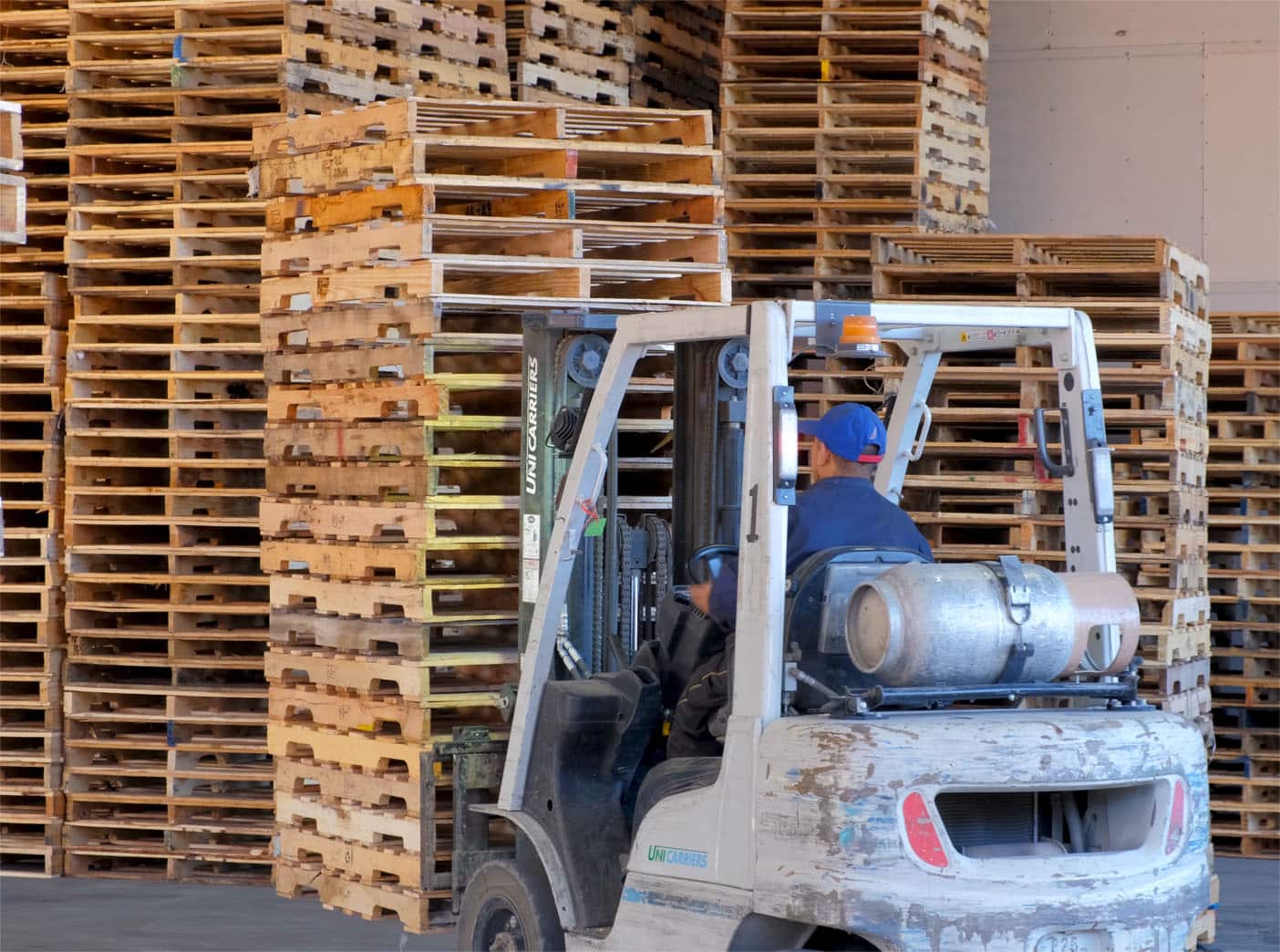 A forklift driver moving some wooden pallets