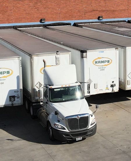 Large white freight trucks and trailers parked at a loading dock