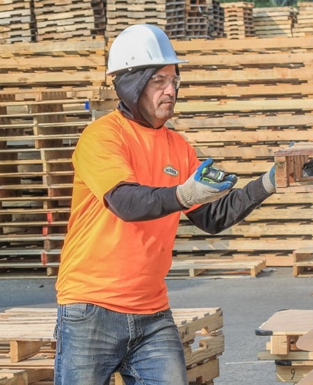 Kamps employee pulling a used pallet from a stack of recycled pallets