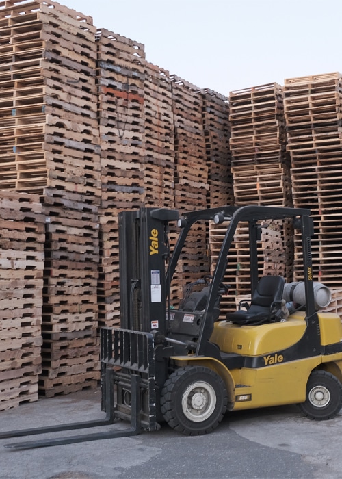 forklift at Kamps Pallets facility in front of stacks of wooden pallets