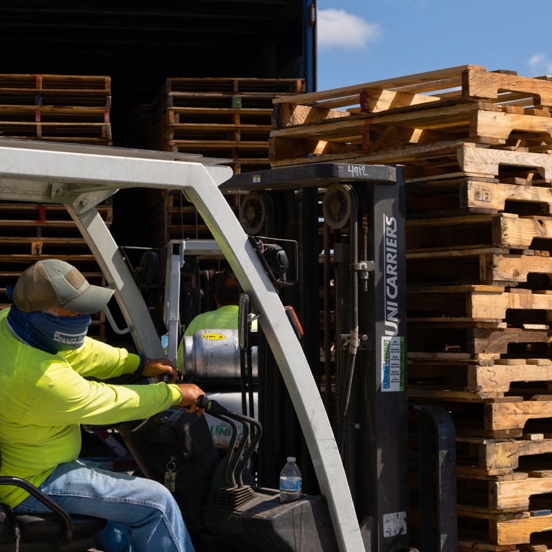 Kamps employee loading up repaired wooden pallets