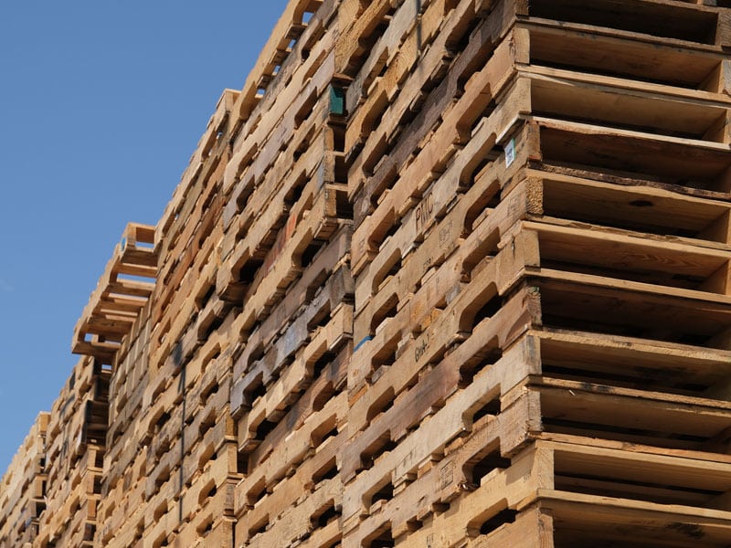 Close up of a large stack of used wooden pallets