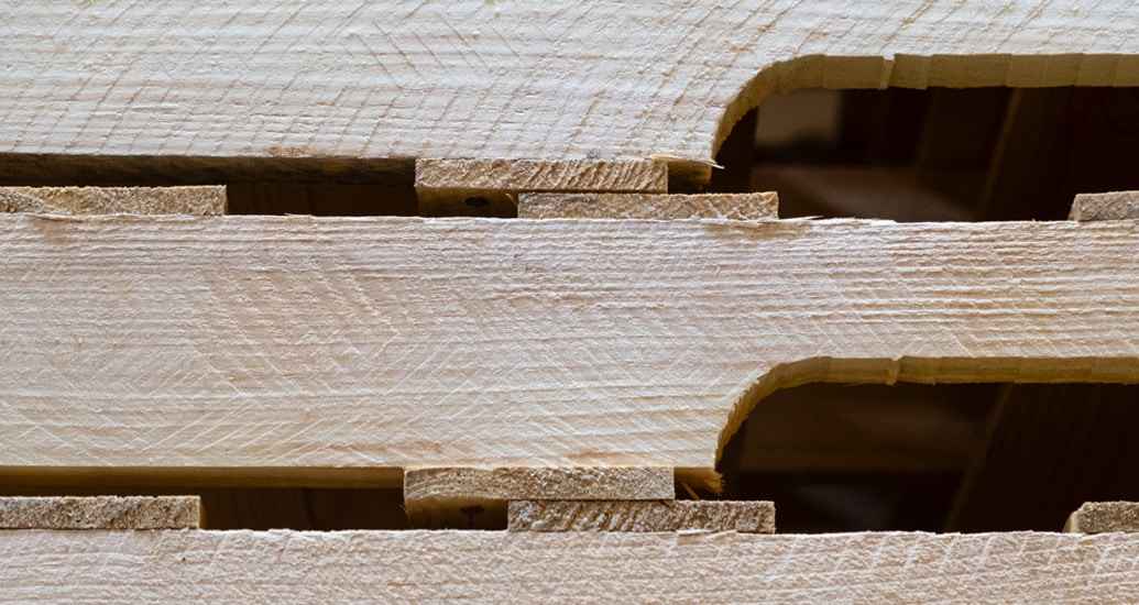 Close-up side view of a string pallet showing the end of a wooden stringer and two deck boards.